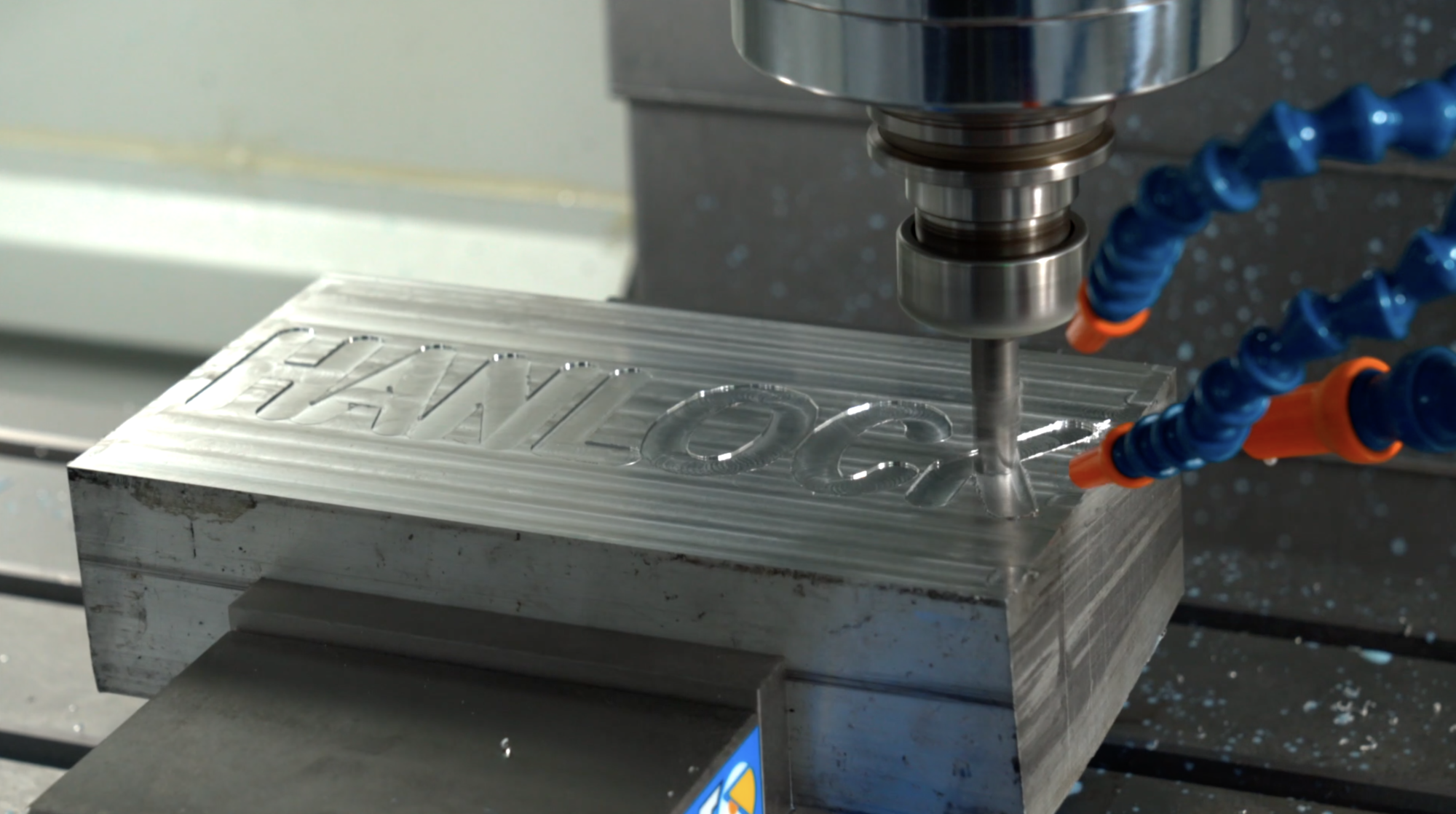 machine carving the word Hanlock into a block of metal